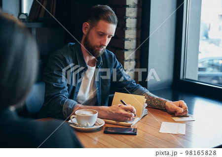 Man hand with pen writing on notebook on a wooden table. Man hand with pen writing on notebook on a wooden table. 98165828