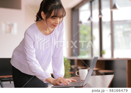 立ったままPCを操作するオフィスの若い女性_1 立ったままPCを操作するオフィスの若い女性_1 98166479