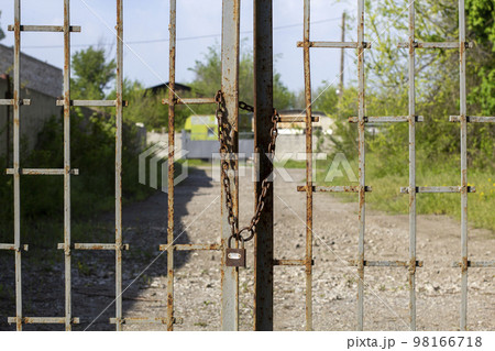 Old rusty iron gate on chain and lock. Closed metal gates. Protection, security and safety concept. padlock on metal gate closeup 98166718