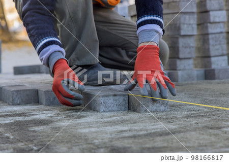 On sand foundation base of house courtyard master is laying gray concrete paving brick slabs laying in lines. On sand foundation base of house courtyard master is laying gray concrete paving brick slabs laying in lines. 98166817