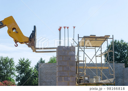 Boom forklift unload concrete blocks in pallets which are being used on construction site. Boom forklift unload concrete blocks in pallets which are being used on construction site. 98166818