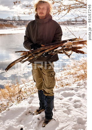 active male gathering wood for fire in forest, nature. handsome guy in warm clothes active male gathering wood for fire in forest, nature. handsome guy in warm clothes 98167246