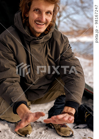 smiling man warm hands by fire, sit next to fire. Travel concept. happy guy smiling man warm hands by fire, sit next to fire. Travel concept. happy guy 98167247