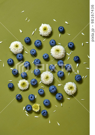 Creative layout made of blueberry and flowers on green background. Flat lay. Creative layout made of blueberry and flowers on green background. Flat lay. 98167436