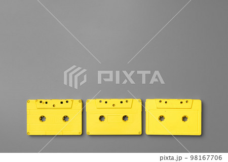 Yellow audio cassettes on gray background top view 98167706