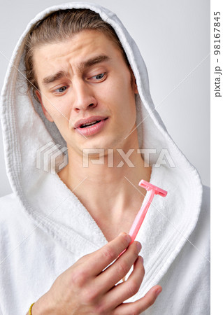 embarrassed guy posing with razor isolated over white background, shaving at first time embarrassed guy posing with razor isolated over white background, shaving at first time 98167845