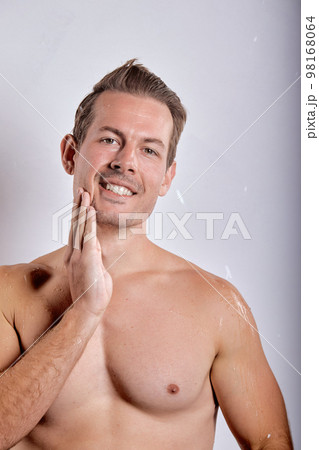 Happy smiling macho man guy holding hands touch perfect skin on face, posing Happy smiling macho man guy holding hands touch perfect skin on face, posing 98168064