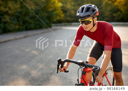 Get faster. Serious young caucasian male racer in sportswear and protective helmet Get faster. Serious young caucasian male racer in sportswear and protective helmet 98168149