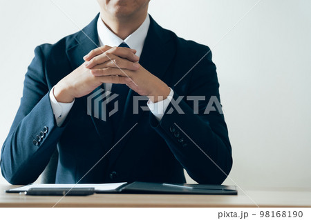 手を組んで話を聞くビジネスマン 98168190