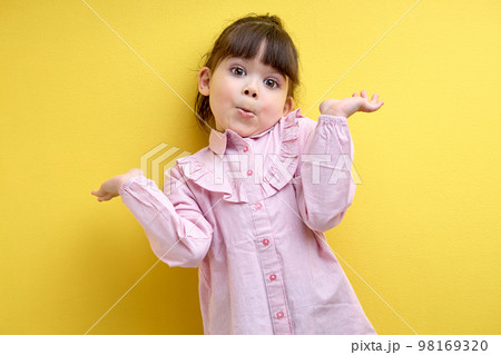 misunderstanding child girl shrugging, i don't know concept. isolated yellow background 98169320