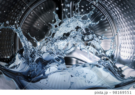 Washing machine drum with clean water flow and splashes. Laundry, washing powder concept. Washing machine drum with clean water flow and splashes. Laundry, washing powder concept. 98169551