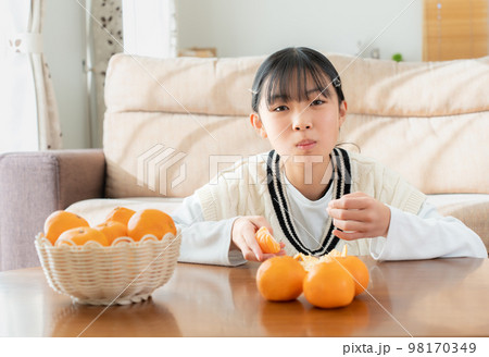 リビングのこたつでみかんを食べているアジア人の女性の写真素材