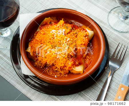 Cannelloni with minced meat and cheese in earthenware dish 98171662