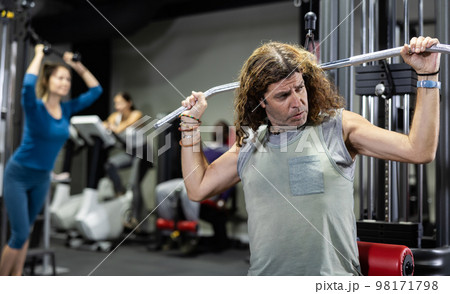 Caucasian man training on lat pull down machine in gym 98171798