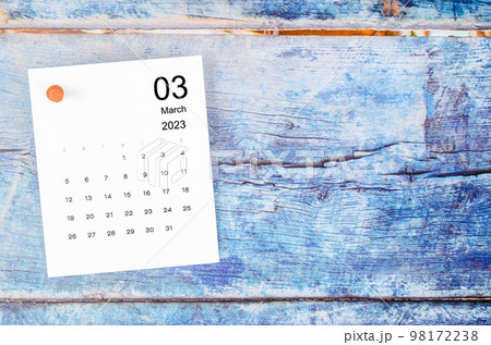 The March 2023 monthly calendar and wooden push pin on blue wooden background. 98172238