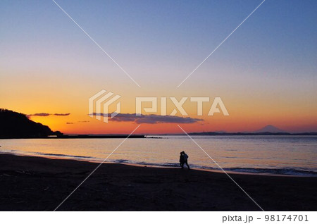 夕暮れどき海岸を散歩する二人 98174701