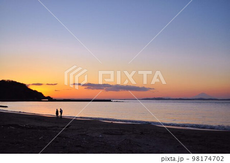 夕暮れどき海岸を散歩する二人 98174702