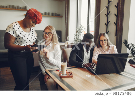 African man. Guy in a black suit. Students with a laptop. Girl in white blouse. International people in a cafe. 98175486