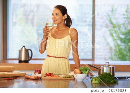 Relaxing with a glass of wine. A young woman enjoying a glass of wine. 98176023