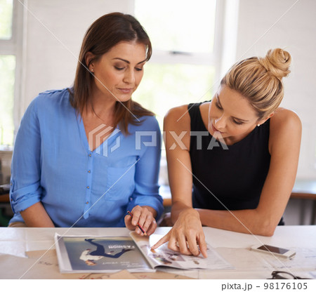 Going over some new designs. a two attractive designers work on a layout. Going over some new designs. a two attractive designers work on a layout. 98176105
