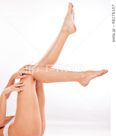 Legs, skincare and beauty with a model woman lying on the floor in studio on a gray background for wellness. Hands, cleaning and feet with a female posing to promote natural skin care cosmetics 98176107