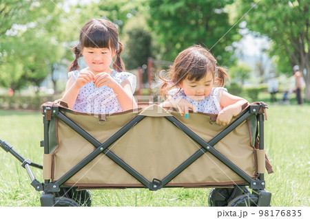 アウトドア・公園でキャリーワゴンに乗って遊ぶ子供（女の子・キャンプ