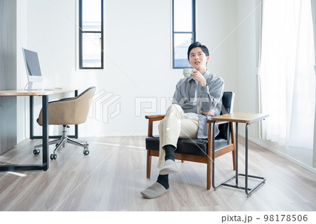 家でコーヒーを飲んでリラックスする若い男性 98178506