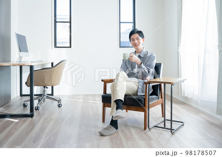 家でコーヒーを飲んでリラックスする若い男性 家でコーヒーを飲んでリラックスする若い男性 98178507