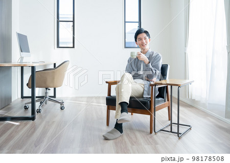 家でコーヒーを飲んでリラックスする若い男性 98178508