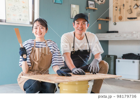 ガレージでノコギリで木を切るアジア人男女(DIY教室・ワークショップ・日曜大工・体験教室) ガレージでノコギリで木を切るアジア人男女(DIY教室・ワークショップ・日曜大工・体験教室) 98179736