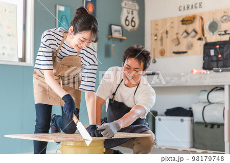 家の倉庫でノコギリで木を切るアジア人男女(DIY教室・ワークショップ・日曜大工・体験教室) 家の倉庫でノコギリで木を切るアジア人男女(DIY教室・ワークショップ・日曜大工・体験教室) 98179748