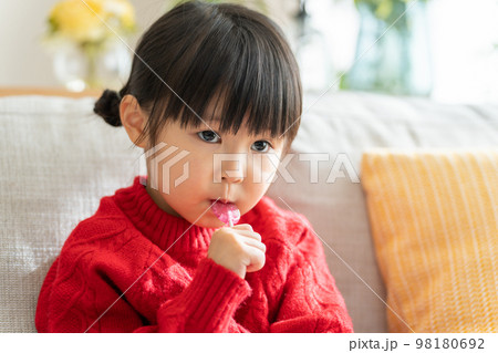 棒付きキャンディーを舐める子供（飴・お菓子） 98180692