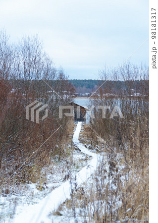 Winter landscape with a view of the lake, bushes and an old fishing hut. Vertical frame. Winter landscape with a view of the lake, bushes and an old fishing hut. Vertical frame. 98181317