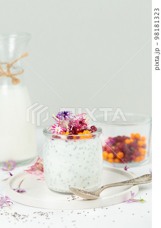 Pudding with chia seeds and edible flowers. Close-up, on a light background, vertical 98181323