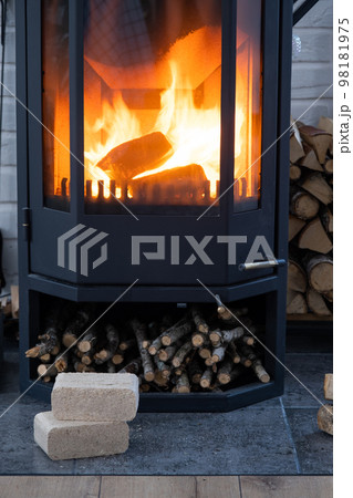 Fuel briquettes made of pressed sawdust for kindling the furnace - economical alternative eco-friendly fuel for the fireplace in the house. Firewood is burning in the oven in the interior 98181975