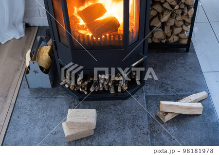 Fuel briquettes made of pressed sawdust for kindling the furnace - economical alternative eco-friendly fuel for the fireplace in the house. Firewood is burning in the oven in the interior 98181978