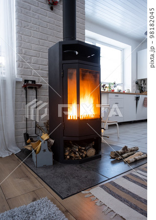 Black stove, fireplace in interior of house in loft style. Alternative eco-friendly heating, warm cozy room at home, burning wood 98182045
