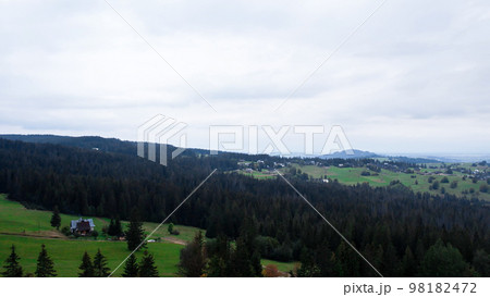 Aerial view of Zakopane town underneath Tatra Mountains taken from the Gubalowka mountain range. Drone High mountains and green hills in summer or spring. Scenic mountain view in Poland 98182472