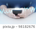 Trader using mobile phone app analytics for cryptocurrency graph. 98182676