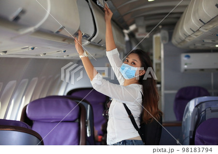 Traveling and Business during COVID-19 virus pandemic concept,woman wearing protective mask sitting near windows on airplane during flight Traveling and Business during COVID-19 virus pandemic concept,woman wearing protective mask sitting near windows on airplane during flight 98183794
