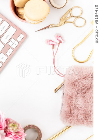 Feminine desktop with gold and pink stationery including a keyboard and mouse 98184420