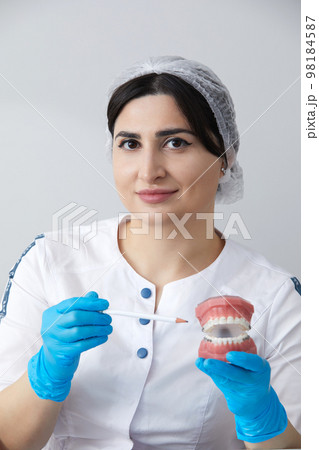 Orthodontist showing model of human jaw with wire braces and aligners explaining the difference 98184587