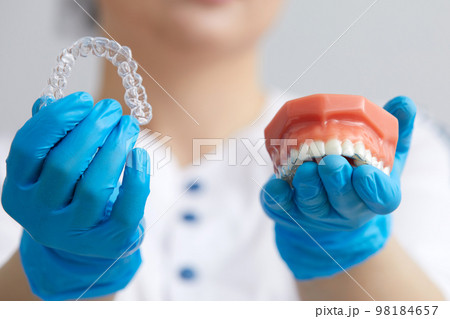 Orthodontist showing the system of aligners on artificial jaws Orthodontist showing the system of aligners on artificial jaws 98184657