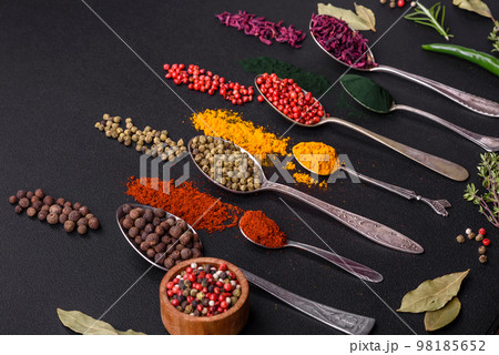 Several types of spices in metal spoons paprika, tomatoes, curry, beets, cumin, turmeric, fennel, spirulina 98185652