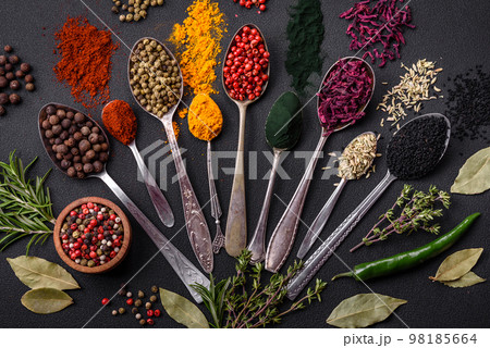 Several types of spices in metal spoons paprika, tomatoes, curry, beets, cumin, turmeric, fennel, spirulina 98185664