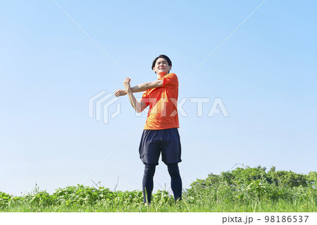 外で準備運動をする男性 98186537