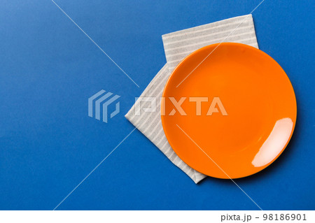 Top view on colored background empty round red plate on tablecloth for food. Empty dish on napkin with space for your design Top view on colored background empty round red plate on tablecloth for food. Empty dish on napkin with space for your design 98186901
