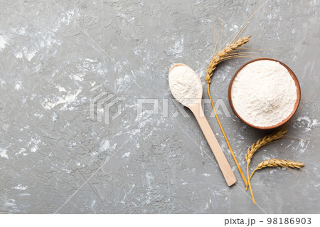 Flat lay of Wheat flour in wooden bowl with wheat spikelets on colored background. world wheat crisis 98186903