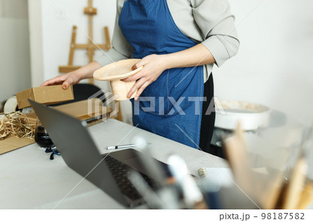Unrecognisable woman entrepreneur, Business owner working at home office with her clay ceramic product. Online selling business work Unrecognisable woman entrepreneur, Business owner working at home office with her clay ceramic product. Online selling business work 98187582
