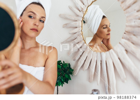 Young woman looking in the bathroom mirror 98188374